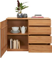 Holzkommode mit offenen Schubladen und Tür, gefüllt mit Geschirr und Büchern, aus der Frontperspektive fotografiert.