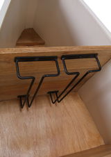 Innenansicht eines Bar-Regals in Bootsform mit Holzregalen und schwarzen Metallhaltern, Perspektive von oben.