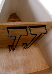 Innenansicht eines Bar-Regals in Bootsform mit Holzregalen und schwarzen Metallhaltern, Perspektive von oben.