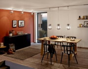 Esszimmer mit modernem Design, hängende Pendelleuchten über einem Holztisch, seitliche Perspektive