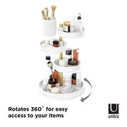 Weißer und goldener drehbarer Organizer mit mehreren Ebenen, gefüllt mit Kosmetikartikeln, aus seitlicher Perspektive.