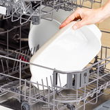 Weiße Auflaufform mit Deckel wird in eine Spülmaschine eingeräumt, seitliche Perspektive.