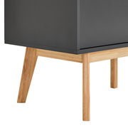 Nahaufnahme eines modernen Sideboards mit dunkler Oberfläche und hellen Holzbeinen, seitliche Perspektive