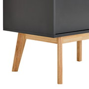 Nahaufnahme eines modernen Sideboards mit dunkler Oberfläche und hellen Holzbeinen, seitliche Perspektive
