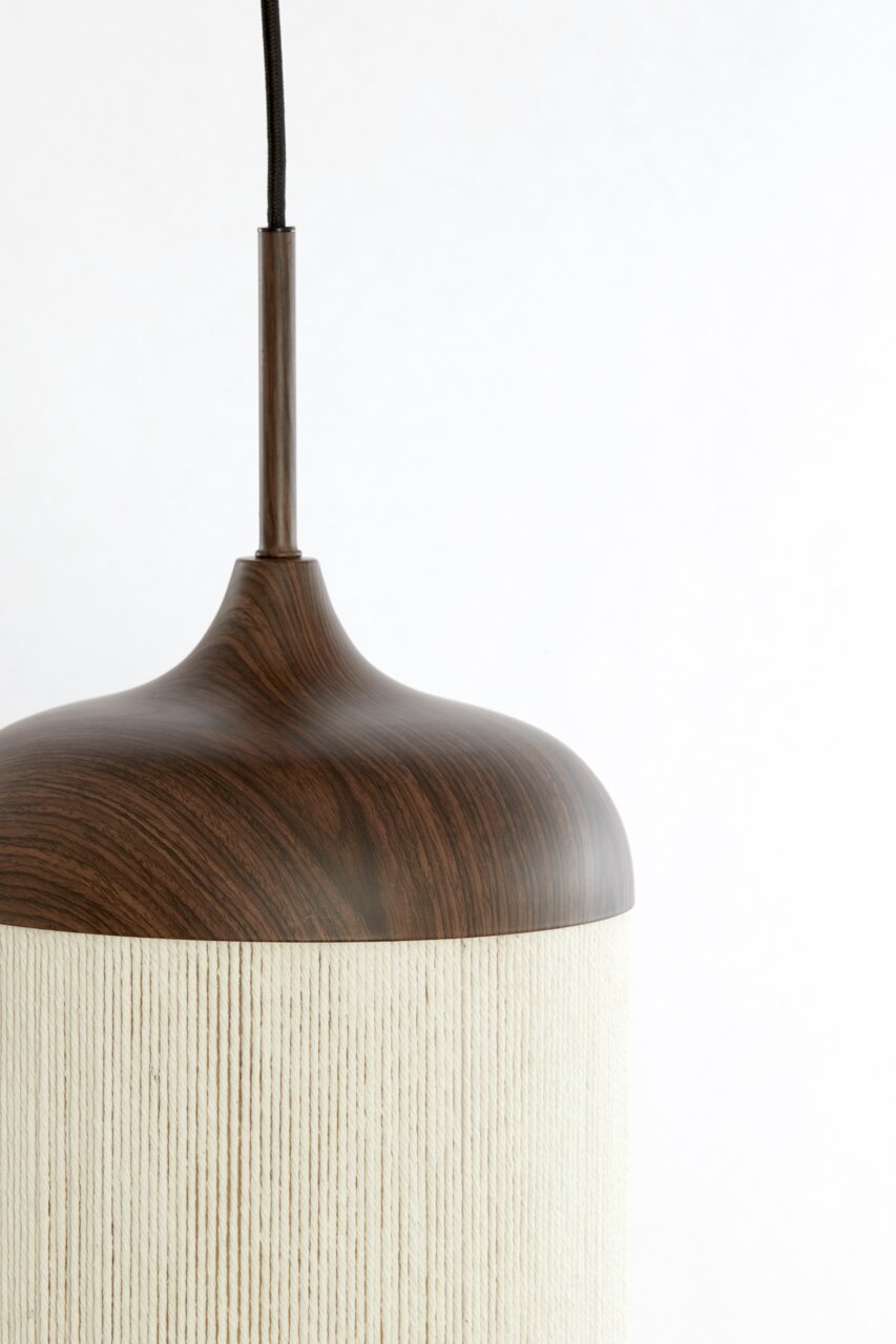 Close-up van een hanglamp met een donkerbruine kap in houtlook en een lichte, geribbelde lampenkap, van voren lichtjes opzij gefotografeerd vanaf boven tegen een witte achtergrond