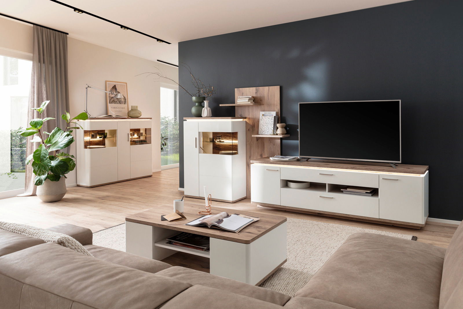 Moderne Wohnzimmer-Wandkombination in heller Holzoptik mit TV-Schrank, Vitrine und Regal, aus der Perspektive eines gemütlichen Wohnzimmers mit Sofa und Couchtisch.
