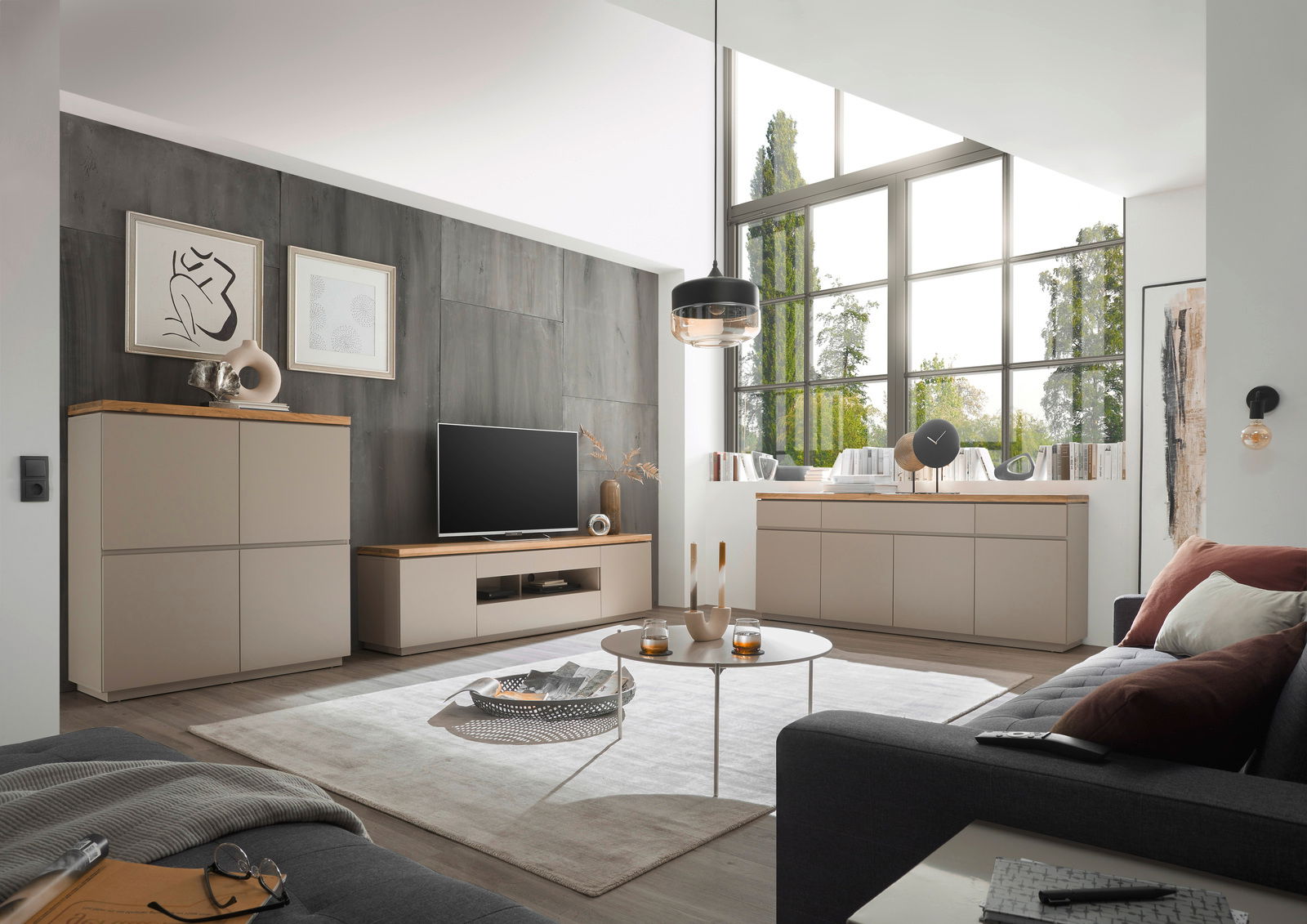 Modernes Wohnzimmer mit XL-TV-Lowboard, Sideboard und Highboard in heller Holzoptik, seitliche Perspektive.