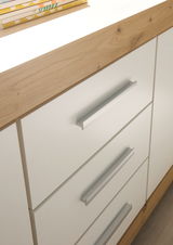 Nahaufnahme eines modernen Sideboards mit weißen Schubladenfronten und Holzoberfläche, seitliche Perspektive