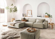 Moderne Rundecke in einem hellen Wohnzimmer mit großen Fenstern, Pflanzen und stilvollen Dekorationen, aus der Perspektive von vorne links.