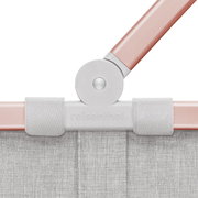 Nahaufnahme des Gelenks eines Carrybag-Rahmens in rosa und grau, mit Stoffdetails und Markenlogo, von vorne betrachtet.