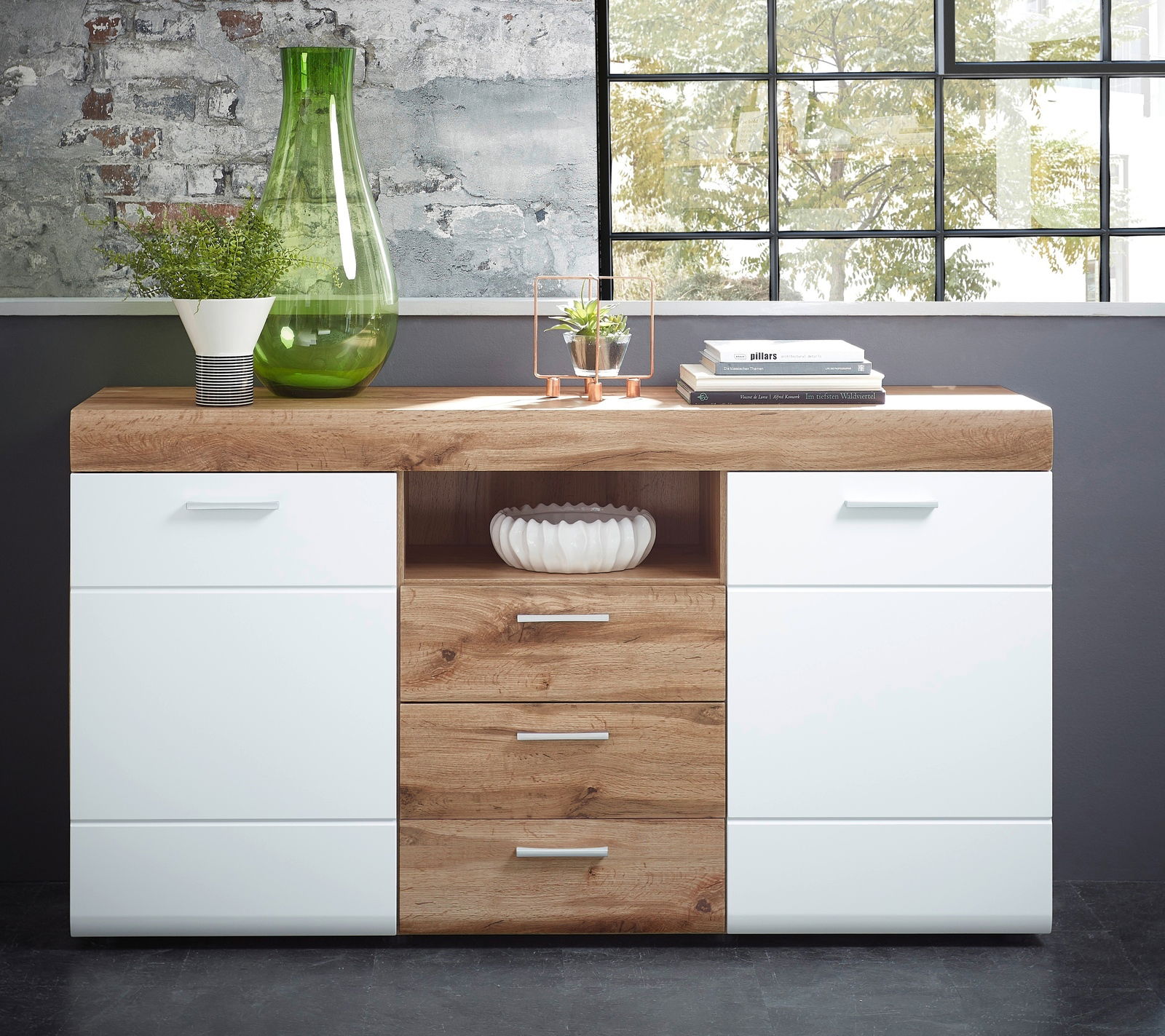 Modernes Sideboard aus Holz und Weiß mit Schubladen und Regalfächern, dekoriert mit Pflanzen und Büchern, aus frontaler Perspektive.