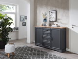 Dunkelgraues Sideboard mit Holzplatte, dekoriert mit Vasen und Büchern, in einem modernen Wohnzimmer. Perspektive von vorne.