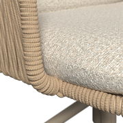 Nahaufnahme eines Armlehnstuhls mit geflochtenem Seil-Design und gepolstertem Sitz, seitliche Perspektive