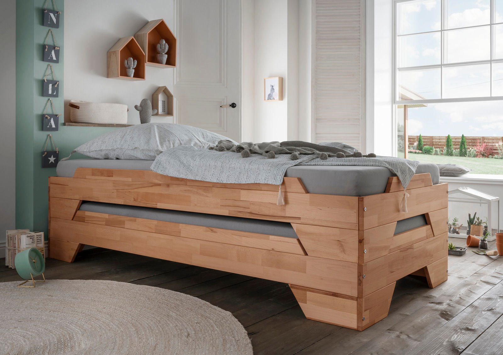 Stapelbett aus Holz in einem hellen Raum mit Blick aus dem Fenster, seitliche Perspektive