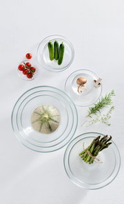 Vogelperspektive auf mehrere Glasschalen mit frischem Gemüse wie Tomaten, Gurken, Pilzen, Spargel und einer Melone.