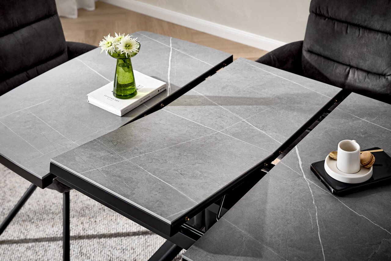 Moderne eettafel met grijze steenlook, uitschuifbaar, met groene vaas en kopje, gezien vanuit vogelperspectief.