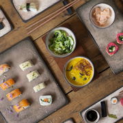 Vogelperspektive auf ein 29-teiliges Sushi-Set in Beige mit verschiedenen Sushi-Varianten und Beilagen auf einem Holztisch.