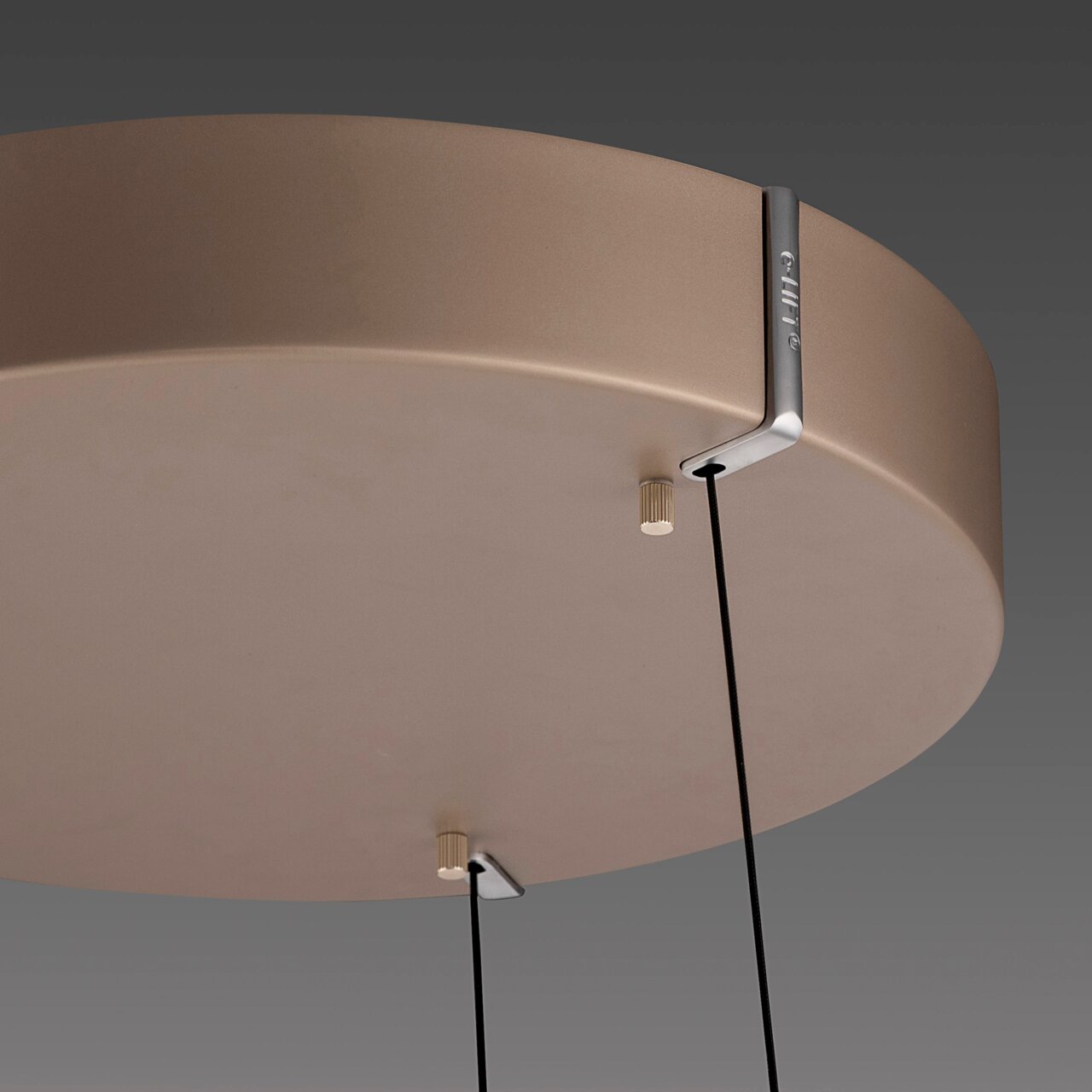 Close-up van de onderkant van een LED-hanglamp met een rond, glad oppervlak en twee kabels die aan het plafond hangen.