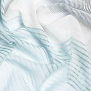 Nahaufnahme eines transparenten Ösenvorhangs mit feinen, horizontalen Streifen in Weiß- und Grautönen.