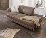 Braune Recamiere mit Armteil links, dekoriert mit einem gemusterten Kissen und einer beigen Decke, in einem modernen Wohnzimmer mit Holzfußboden. Perspektive von vorne links.