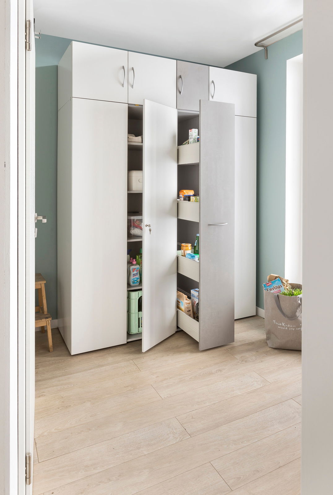 Mehrzweckschrank in einem Raum mit geöffneter Tür, gefüllt mit Haushaltsgegenständen, aus einer seitlichen Perspektive fotografiert.