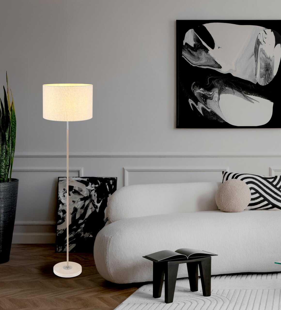 Moderne staande lamp met een lichte lampenkap in een stijlvol ingerichte woonkamer, gezien vanaf de zijkant.