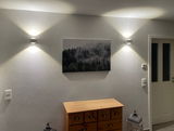 LED Wandleuchte an einer Wand montiert, mit nach oben und unten gerichteten Lichtstrahlen, Perspektive von vorne.