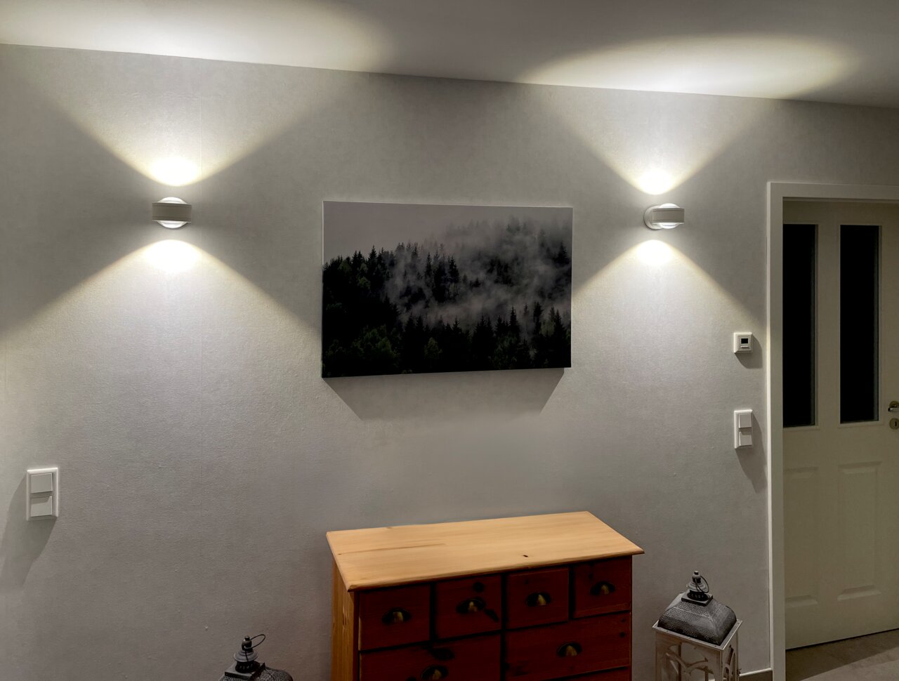 Megatron LED-Wandleuchte DUE PUNTO - UP & DOWN LED Wandleuchte an einer Wand montiert, mit nach oben und unten gerichteten Lichtstrahlen, Perspektive von vorne.