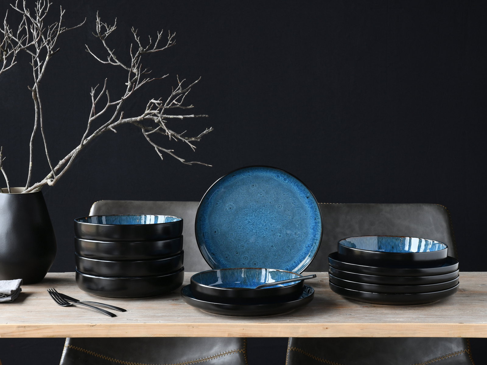 Creatable Tafelservice 12-tlg NORDIC FJORD Elegantes Tafelservice 12-tlg in Schwarz und Blau, seitliche Perspektive, auf einem Holztisch arrangiert mit dekorativem Ast im Hintergrund.