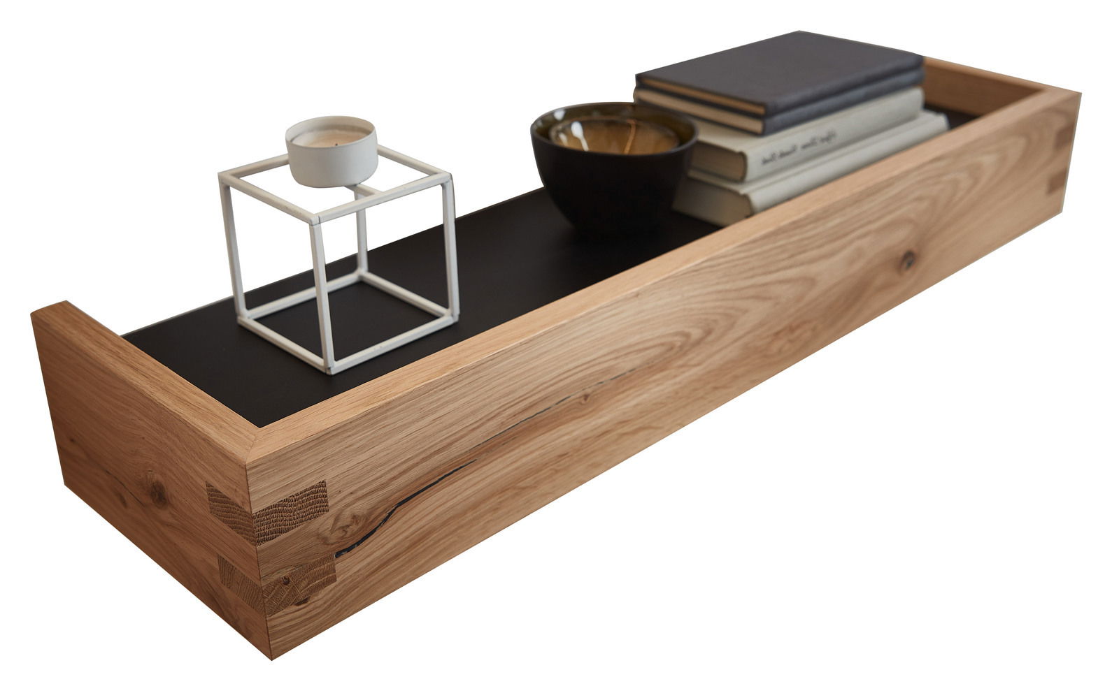 Wandboard aus Holz mit schwarzer Ablagefläche, dekoriert mit Kerzenhalter, Schale und Büchern, seitliche Perspektive