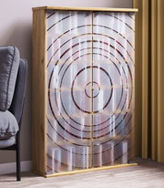 Holzschrank mit zwei satinierten Glastüren und konzentrischem Kreisdekor, in schräger Vorderansicht im Wohnraum neben einem Sofa