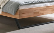 Nahaufnahme eines modernen Bettgestells aus Holz mit Metallbeinen, seitliche Perspektive