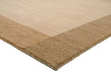 Beiger Wollteppich mit breitem Rand in einer dunkleren Beige-Nuance, perspektivisch von der Seite aufgenommen.