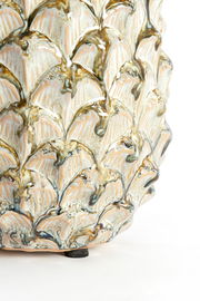 Nahaufnahme eines kunstvoll verzierten Ornaments mit blattähnlichem Muster und glänzender Oberfläche, seitliche Perspektive.