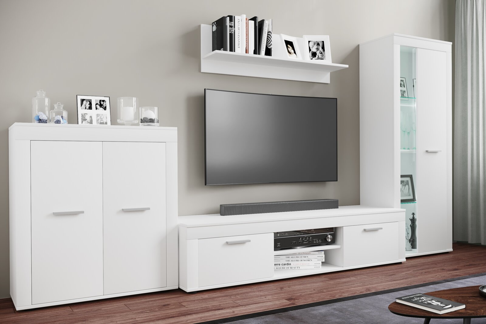 Modernes weißes Wohnzimmermöbel-Set mit TV-Lowboard, Wandregal, Vitrine und Sideboard, frontal aus leicht schräger Perspektive fotografiert TV und Deko sind zu sehen.