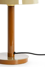 Nahaufnahme einer Tischleuchte mit braunem Standfuß und beigem Lampenschirm, seitliche Perspektive.