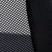 Nahaufnahme eines schwarzen Netzstoffs und eines glatten Stoffes, vermutlich Teil eines Drehstuhls, aus seitlicher Perspektive.