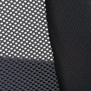 Nahaufnahme eines schwarzen Netzstoffs und eines glatten Stoffes, vermutlich Teil eines Drehstuhls, aus seitlicher Perspektive.