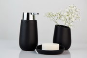 Schwarzer Keramik-Seifenspender mit glänzendem Chrom-Pumpkopf, frontal fotografiert, neben einer passenden Vase mit weißen Blumen und einer Seifenschale.