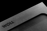 Nahaufnahme eines grauen Schneidebretts mit der Aufschrift 'WOLL', diagonale Perspektive.