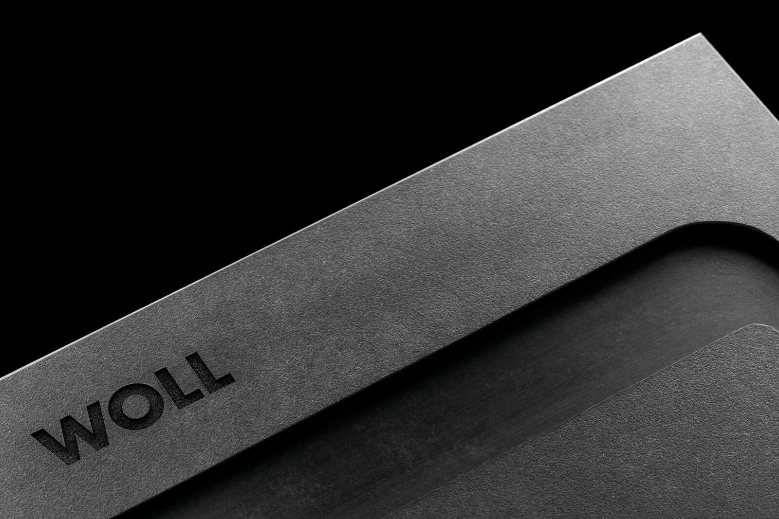 Nahaufnahme eines grauen Schneidebretts mit der Aufschrift 'WOLL', diagonale Perspektive.