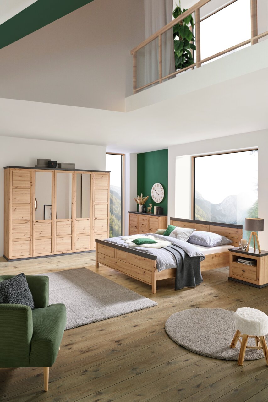 Schlafzimmer mit einem Bett aus Holz in der Größe 140x200 cm, umgeben von passenden Möbeln, aus der Perspektive von vorne rechts betrachtet.