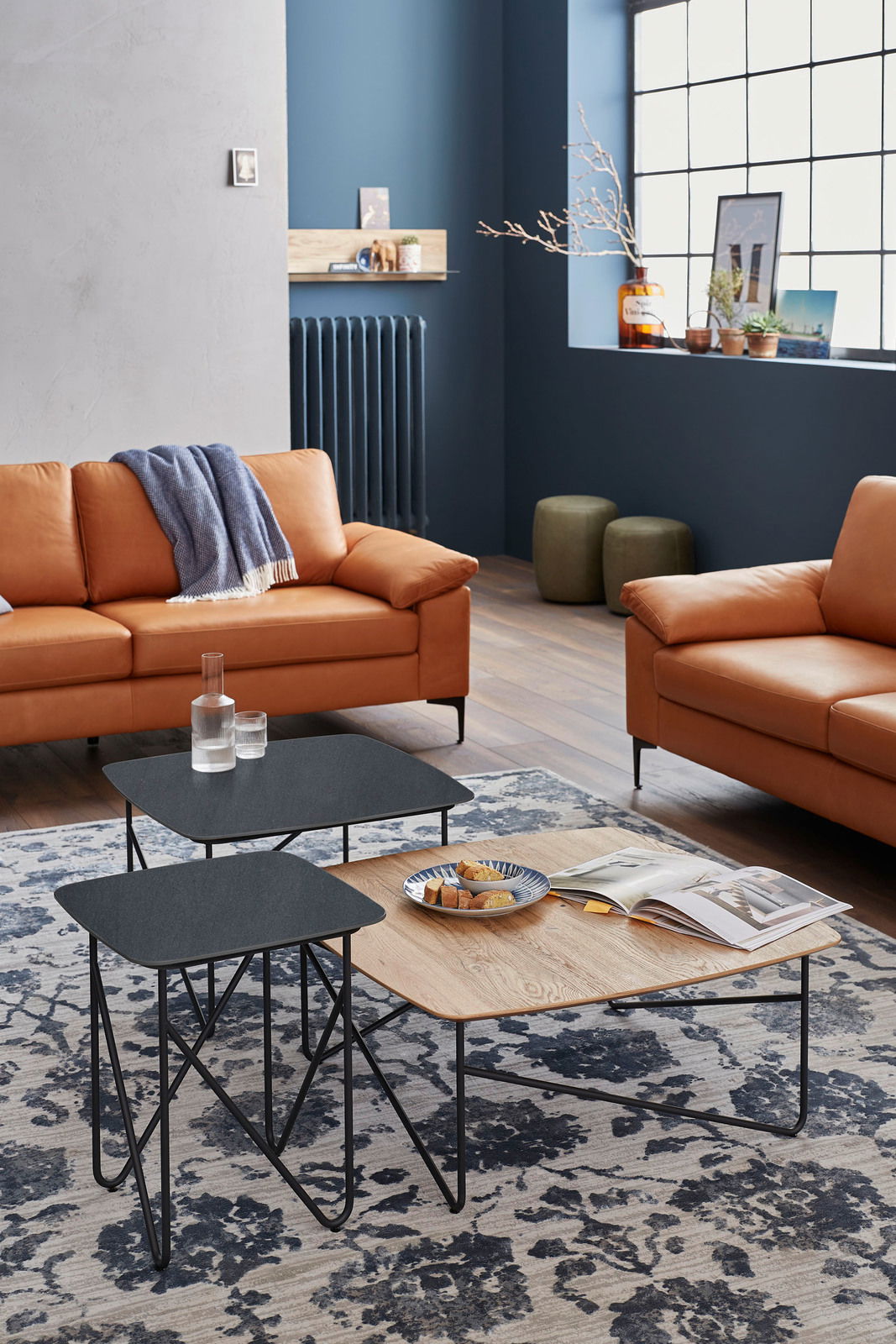 Moderner Couchtisch mit schwarzer und holzfarbener Oberfläche, aus der Perspektive eines gemütlichen Wohnzimmers mit Ledersofas und dekorativem Teppich.