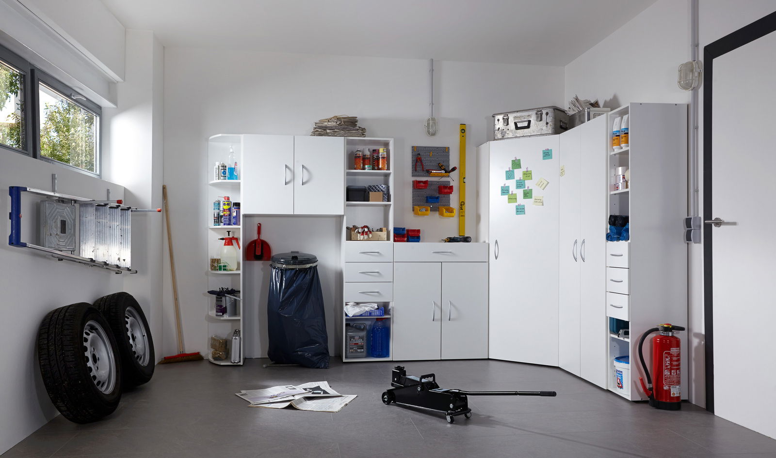 Mehrzweckschränke und Regale in einer Garage, frontal fotografiert. Die Schränke sind weiß und bieten Stauraum für verschiedene Haushaltsgegenstände.