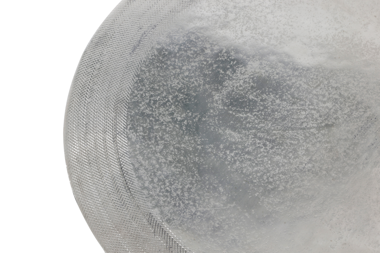 Nahaufnahme eines silbernen Beistelltisches mit strukturierter Oberfläche, von oben betrachtet.