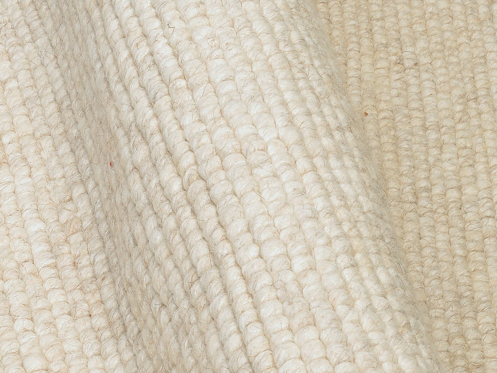 Nahaufnahme eines handgewebten Teppichs in cremeweißer Farbe mit sichtbarer Textur und Struktur.