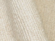 Nahaufnahme eines handgewebten Teppichs in cremeweißer Farbe mit sichtbarer Textur und Struktur.