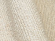 Nahaufnahme eines handgewebten Teppichs in cremeweißer Farbe mit sichtbarer Textur und Struktur.