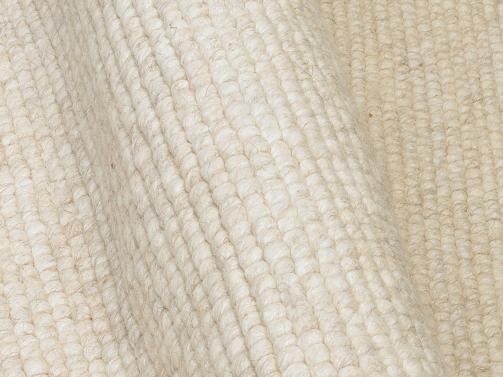 Nahaufnahme eines handgewebten Teppichs in cremeweißer Farbe mit sichtbarer Textur und Struktur.