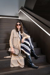 Frau sitzt auf einer Treppe mit einer beigen Tasche in der Hand, seitliche Perspektive